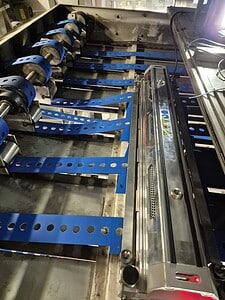 Conveyor belt with blue belts and rollers for material handling.