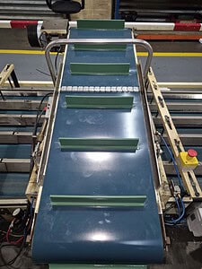 Industrial conveyor belt with green guides for material handling.